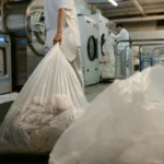 Pekerja membawa tas cucian di fasilitas laundry komersial